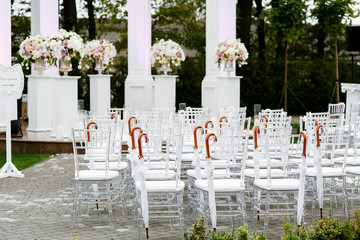 White chairs with umbrellas on their backs stand in rows waiting