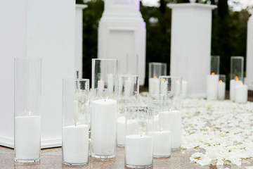 Tall vases with white burning candles stand around circle covere
