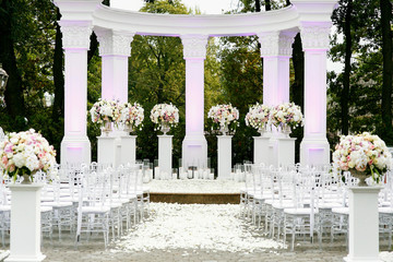 White pillars with bouquets of roses surround place prepared for