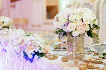 Large vase with beautiful roses stands on rich served dinner tab