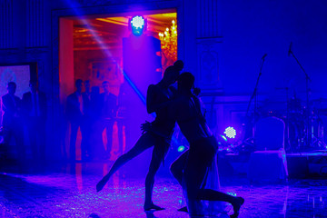 Silhouettes of dancers moving in blue lights