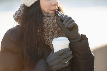 Young white girl vaping outdoor in winter