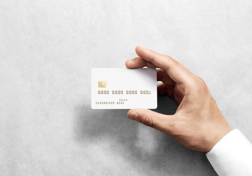 Hand holding blank white credit card mockup with chip and embossed gold info. Plain plastic bank-card display front, design mock up. Electronic money holder template.
