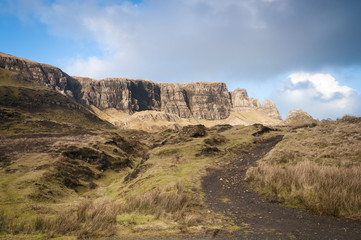 Sunshine over the Quiraing on the Inner Hebride Island of Isle of Skye with the footpath up to it in the foreground.