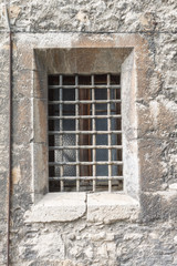 Fototapeta na wymiar window with bars. background of the old castle of gray. Old window in a rectangular stone building.