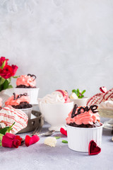 Beautiful chocolate cupcake, pink cream, meringue cookies and red roses on gray stone background. Valentines, Mother Day, wedding concept with copy space.