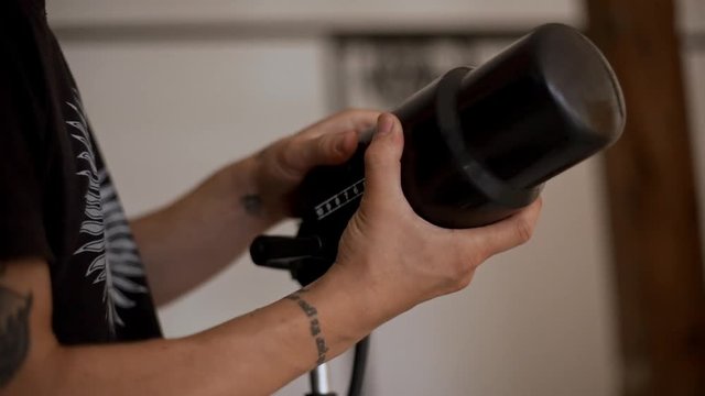 Close up hands of young man getting setting up lighting equipment. Slow motion.
