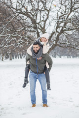 Fototapeta na wymiar Happy loving couple walking in winter park enjoying snow