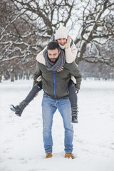 Happy loving couple walking in winter park enjoying snow