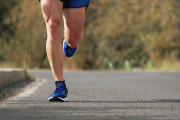 Runner man running on road training for marathon run doing high intensity interval training sprint 