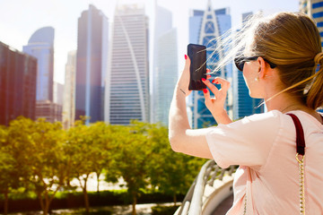 Fototapeta premium Look from behind at blonde lady taking picture on her iPhone sta