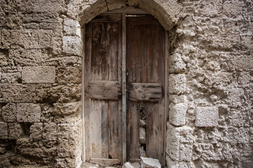 Fototapeta na wymiar Old wooden door in the wall. Greece, Rhodes