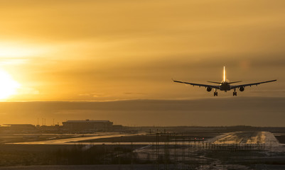 Fototapeta na wymiar Commercial airliner landing to airport runway at sunset