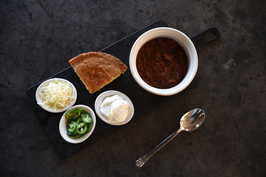 Chilli con carne, cornbread and accompaniments, overhead view