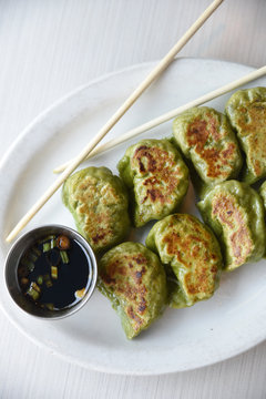 Dumplings with dipping sauce and chopsticks on plate