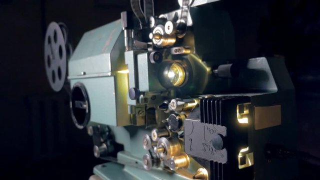 Film projector. Old movie projector working in dark. Dolly shot. 4K.