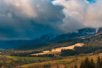 Beautiful dramatic clouds over mountains. Sunlight spots on the forest hills at Carpathian mountains. Ukraine.