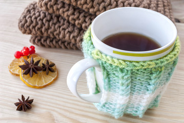 Cup of hot tea with lemon and warm winter scarf on brown wooden tabletop