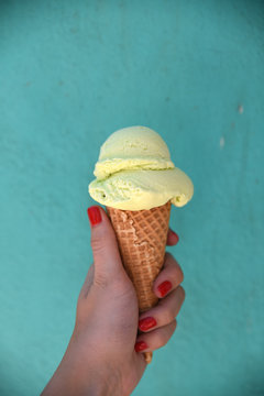 Hand holding ice cream cone, turquoise background 