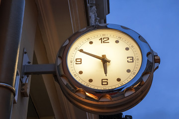 Naklejka premium Street clock with backlight on the background of blue night sky. The center of Vilnius, Lithuania