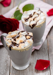 S'mores drink. Two mugs of hot chocolate with marshmallows on a wooden table. Cocoa. Rose petals. Valentine.