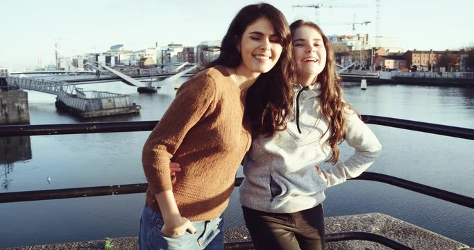 Portrait of two happy teenager friends hugging and looking to camera with smile in front of Drogheda River. Shot on RED EPIC 2016.