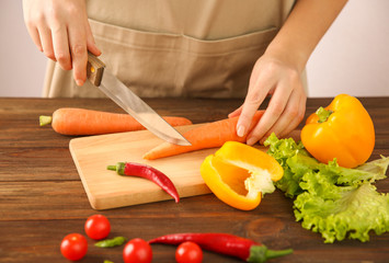 Woman chopping fresh vegetables on cutting board