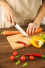 Woman chopping fresh vegetables on cutting board