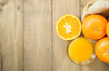 orange juice in glass and sliced orange in gunny sack on wood table top with copy space, top view
