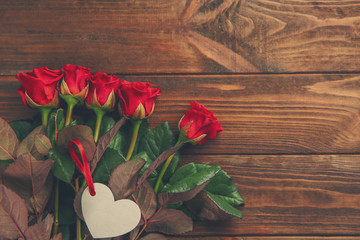 Naklejka na ściany i meble Beautiful red roses with card on wooden background