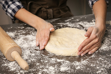 Young woman making dough in kitchen, closeup