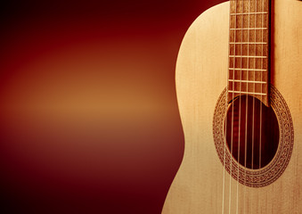 Part of a orange acoustic guitar on black background.