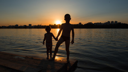 Boy and girl holding hands at sunset. Silhouette frame