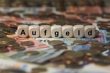 aufgeld - Holzwürfel mit Buchstaben im Hintergrund mit Geld, Geldscheine