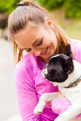 Smiling woman holding french bulldog outside