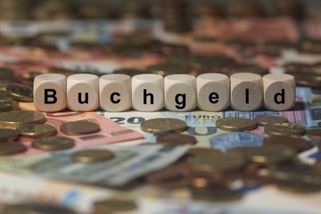 buchgeld - Holzwürfel mit Buchstaben im Hintergrund mit Geld, Geldscheine