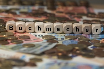 buchmacher - Holzwürfel mit Buchstaben im Hintergrund mit Geld, Geldscheine