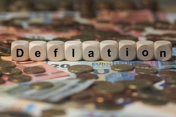 deflation - Holzwürfel mit Buchstaben im Hintergrund mit Geld, Geldscheine