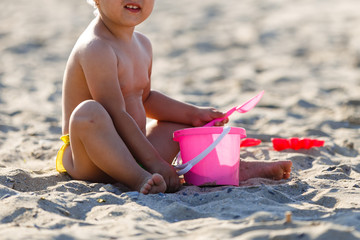 Baby playing on the sandy beach near the sea