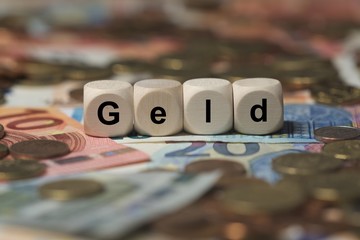 geld - Holzwürfel mit Buchstaben im Hintergrund mit Geld, Geldscheine
