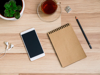 Wooden table with smartphone and Cup of tea, Desk. The view from the top