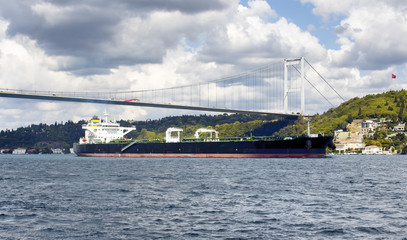 Big, dry cargo ship / vessel crosses Bosphorus strait in Istanbul. Asian side and FSM (Fatih Sultan Mehmet) bridge are in the background. It is significant waterway located in northwestern Turkey