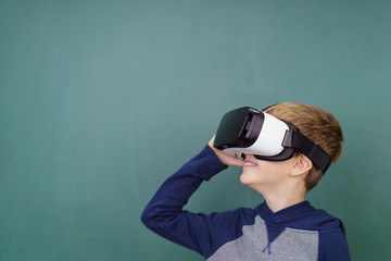 junge mit virtual reality brille steht vor einer schultafel
