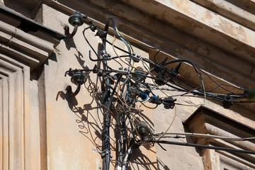 Obraz na płótnie Canvas Dangerous installation of electricity cables and wires on the wa