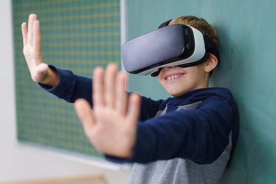 kleiner junge mit virtual reality brille streckt die hände nach vorne
