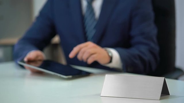 Man in business suit working on tablet pc, blank nameplate template for text