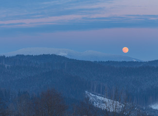 Winter landscape in the mountains at night. A full moon and a starry sky. Carpathians, Ukraine