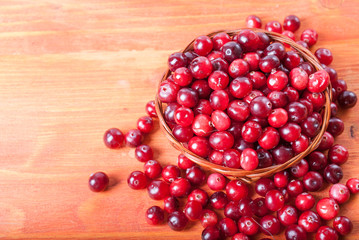 Basket with ripe cranberries on a wooden background