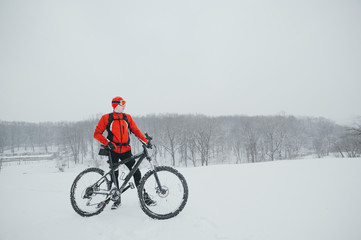 cyclist in red in the winter snowy forest