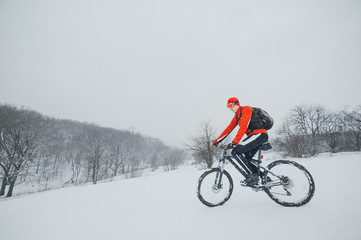 Fototapeta na wymiar Extreme cyclist rides in the winter snowy forest